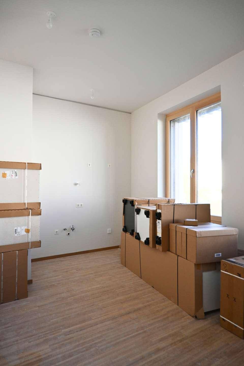 Leerer Raum mit hellem Holzfußboden, einem großen Fenster und weißen Wänden, bereit zur Gestaltung.