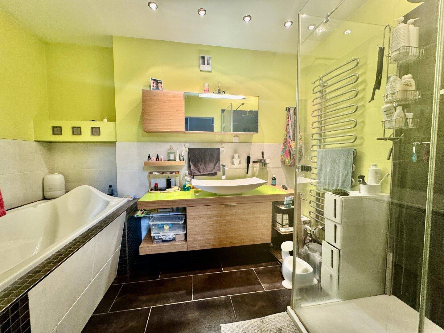 Modernes Badezimmer mit grünen Wänden, Badewanne, begehbarer Dusche und stilvollem Waschtisch.