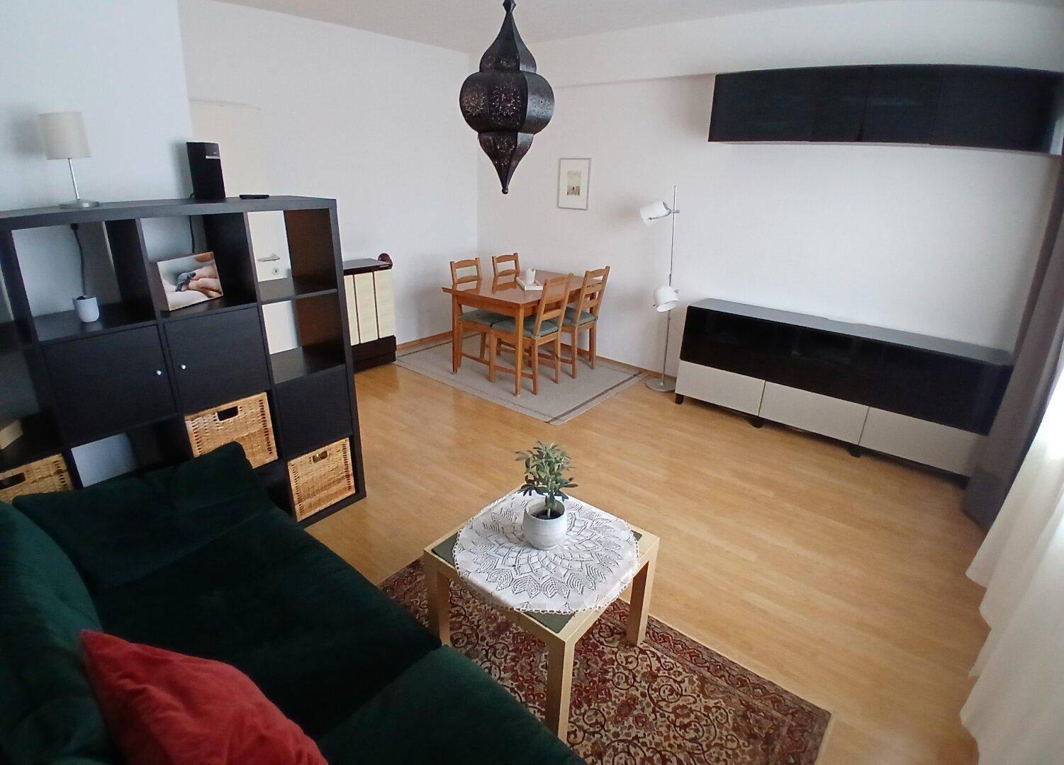 Geräumiger Wohn-Essbereich mit Sofa, Esstisch und einem marokkanisch anmutenden Deckenlicht.