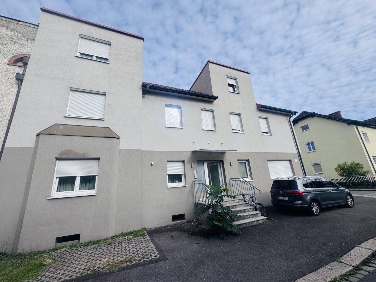 Eingangsbereich des Mehrfamilienhauses mit moderner Fassade und gepflegter Umgebung.