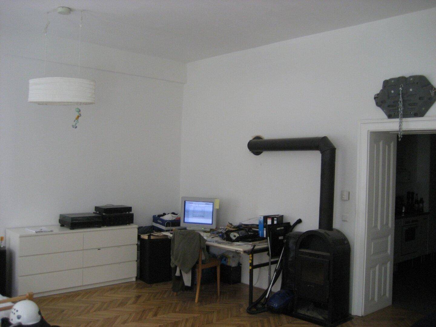 Wohnbereich mit Schreibtisch, Computer und einem traditionellen Holzofen für zusätzliche Wärme.