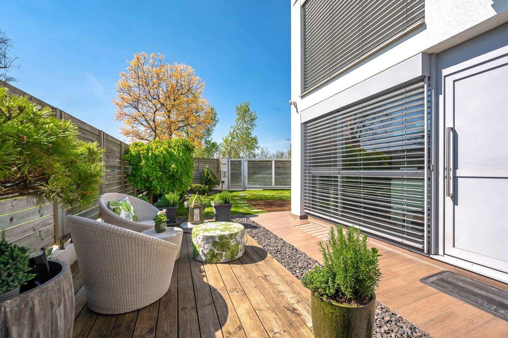Gemütliche Terrasse mit Holzboden und modernen Sitzgelegenheiten, direkt am Gebäude gelegen.