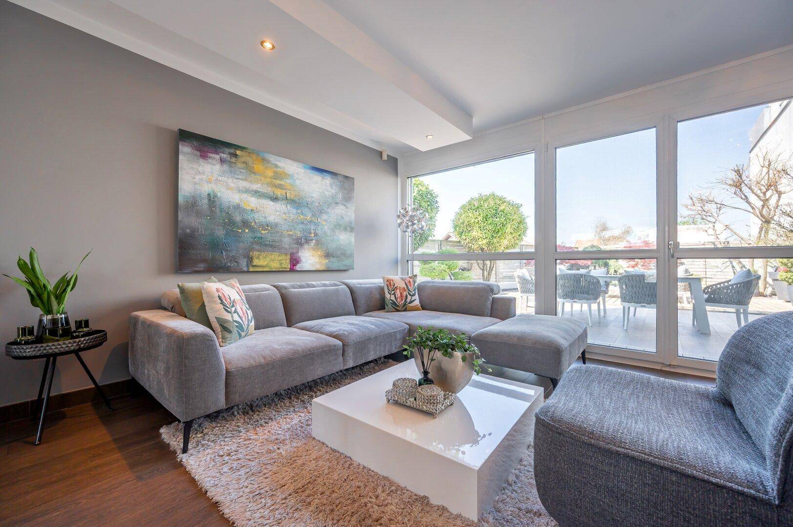 Helles Wohnzimmer mit großem Ecksofa, modernem Couchtisch und Zugang zur Terrasse.