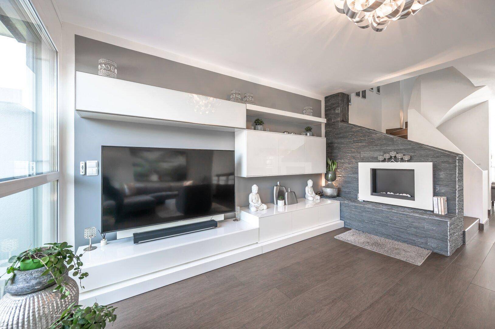 Modernes Wohnzimmer mit integrierter Medieneinheit, Kamin und Treppenaufgang.