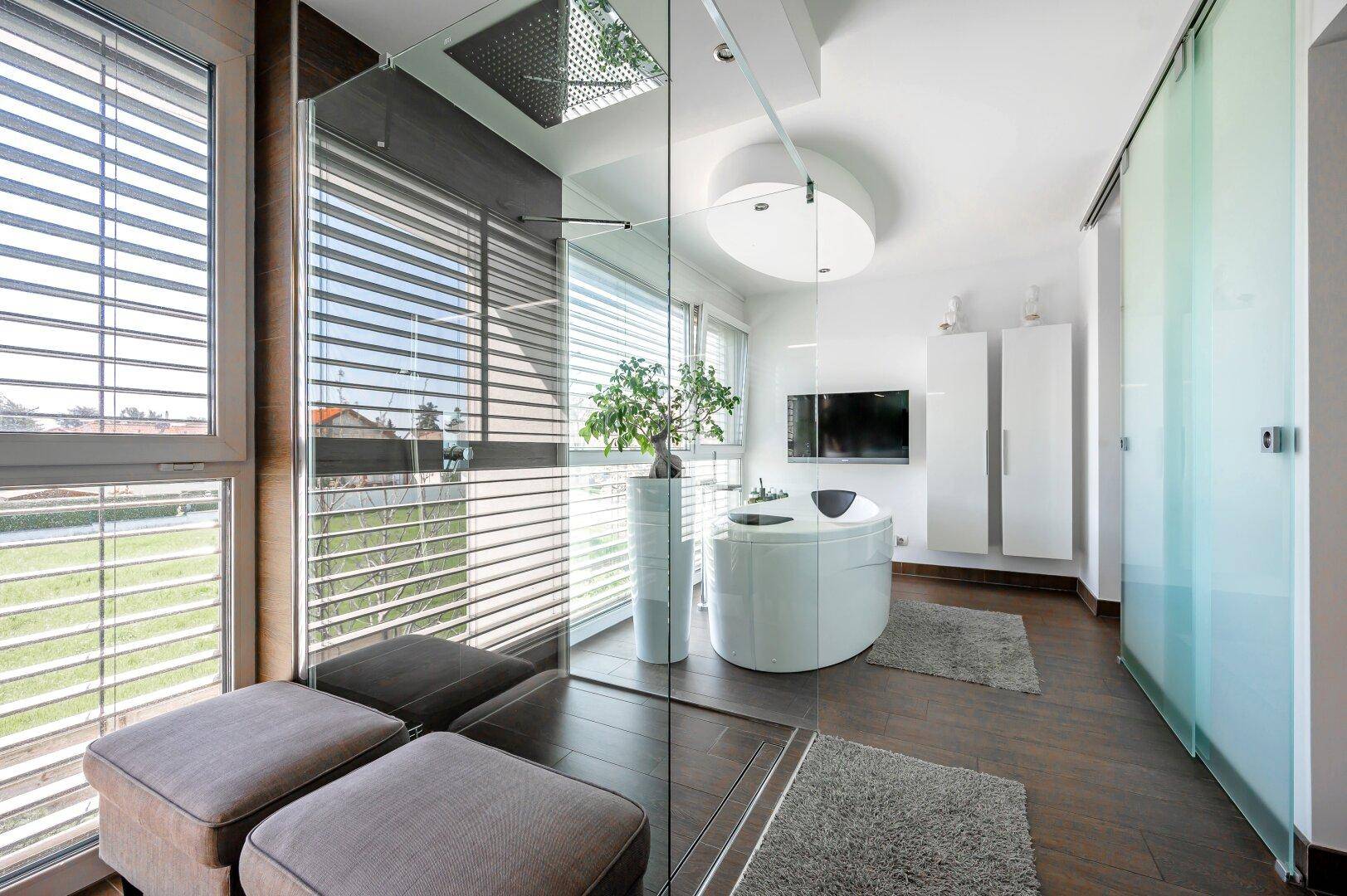 Helles Badezimmer mit großer Glasdusche, Sitzgelegenheiten und Blick nach draußen.