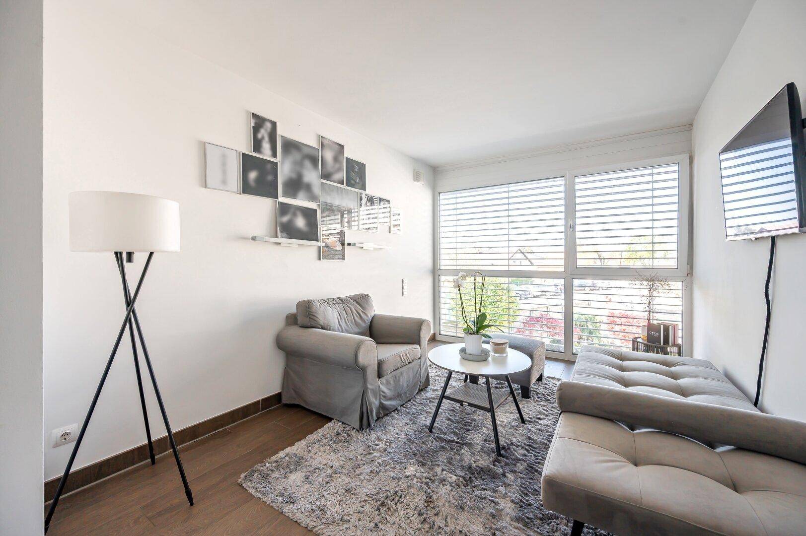 Gemütliches Zimmer mit Sessel, Couch und großem Fenster, ideal als Gäste- oder Arbeitszimmer.