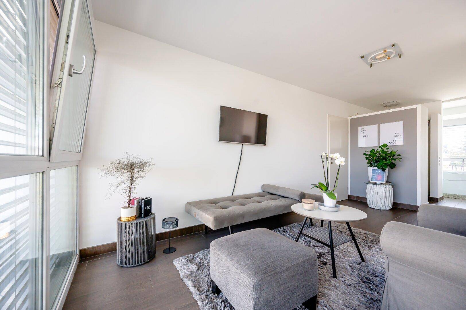 Helles Zimmer mit Tagesbett, modernem Beistelltisch und Blick nach draußen.