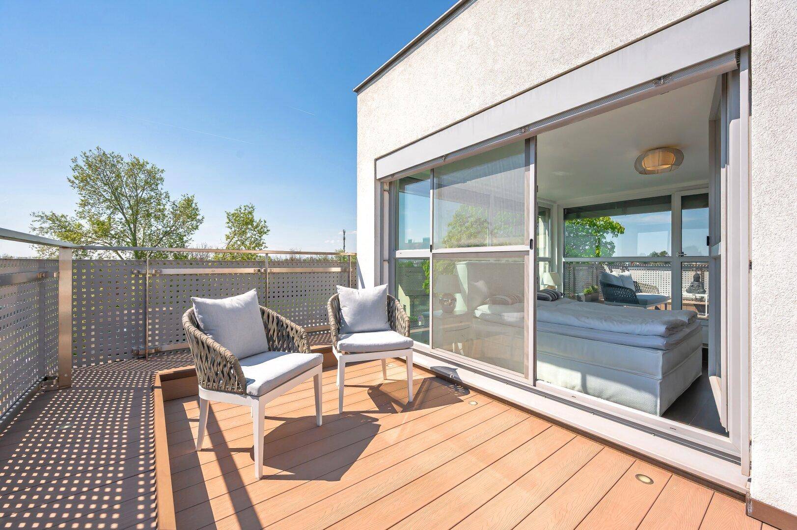 Geräumiger Balkon mit modernen Sitzmöbeln und Zugang zum Schlafzimmer.