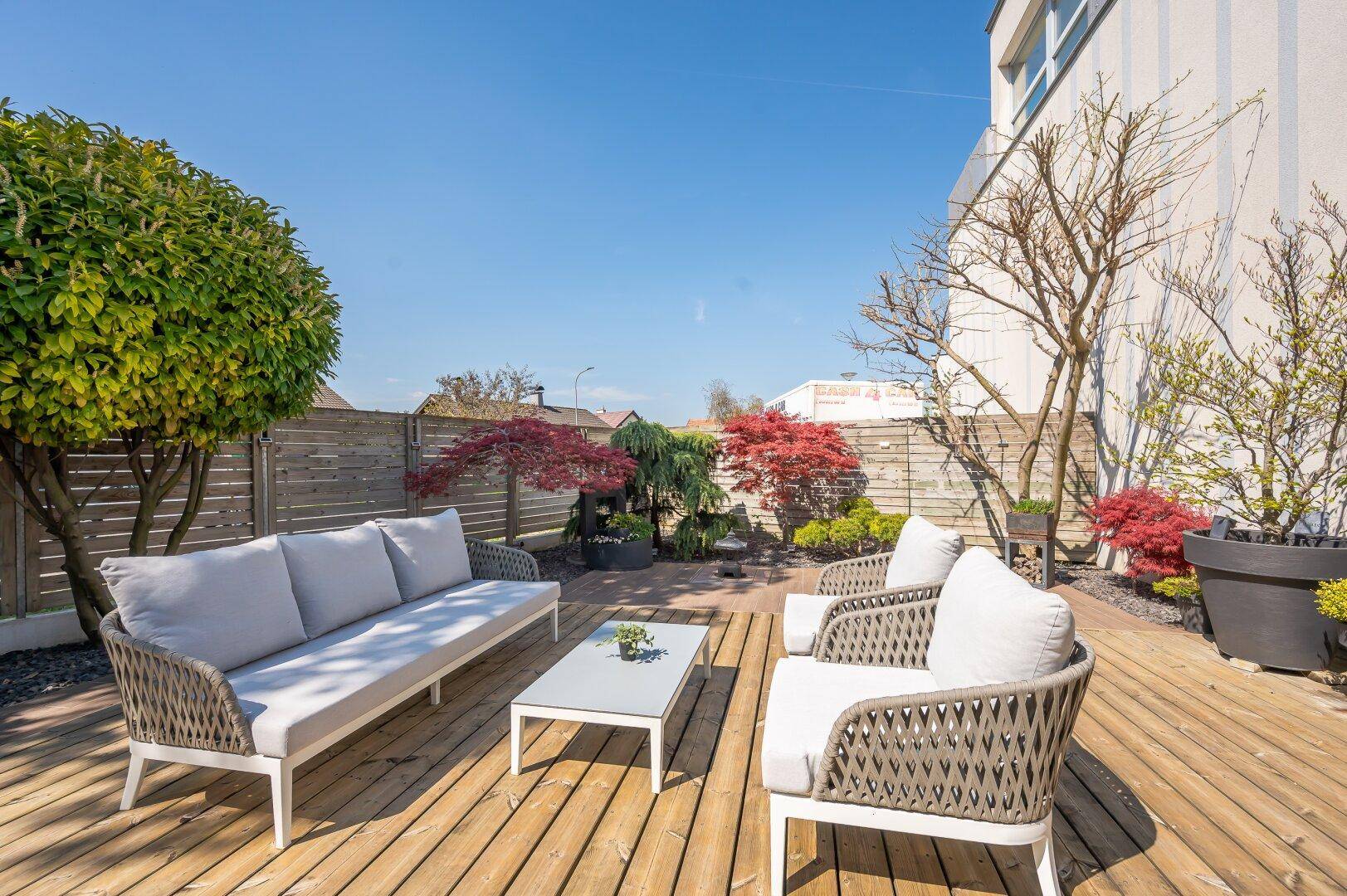 Sonnige Terrasse mit bequemen Lounge-Möbeln und Blick auf den Gartenbereich.