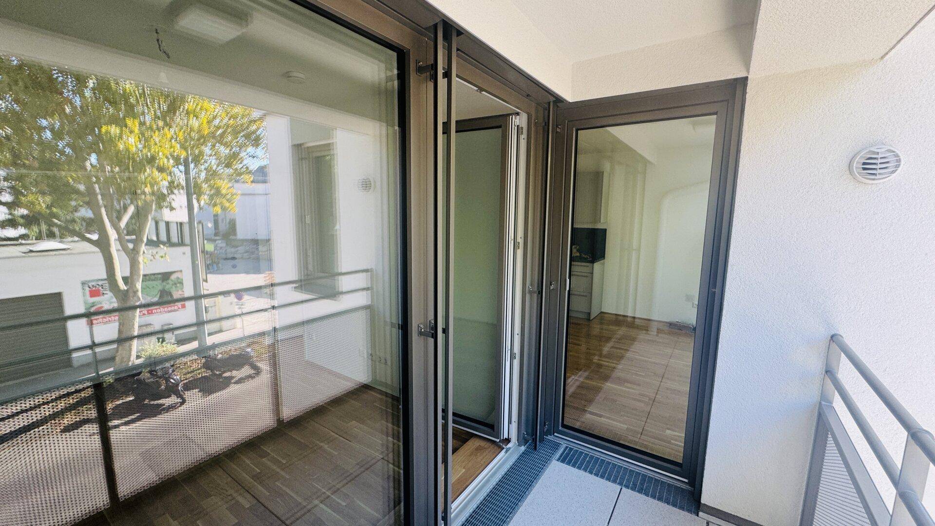 Moderner Balkon mit Glasgeländer und Blick auf die Umgebung.