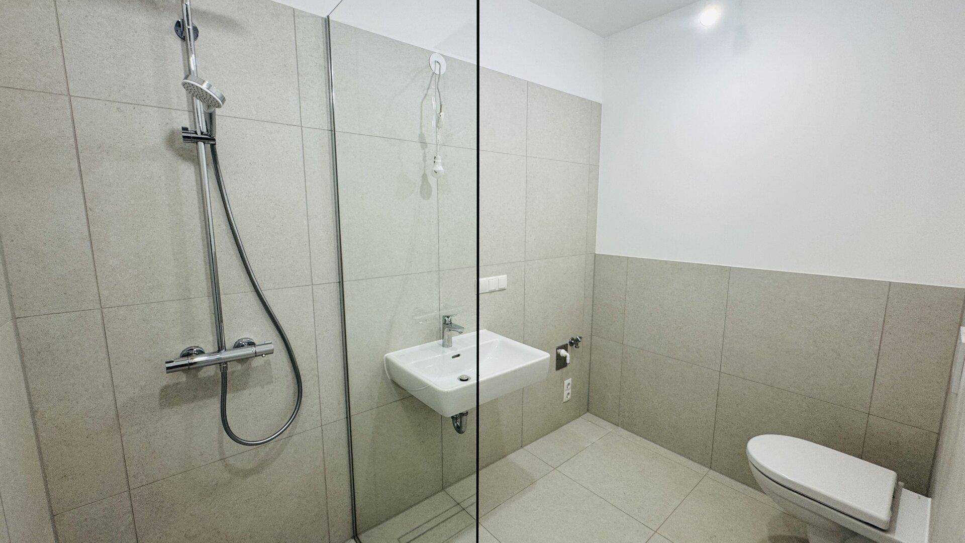 Helles Badezimmer mit ebenerdiger Dusche, Wand-WC und modernem Waschbecken.