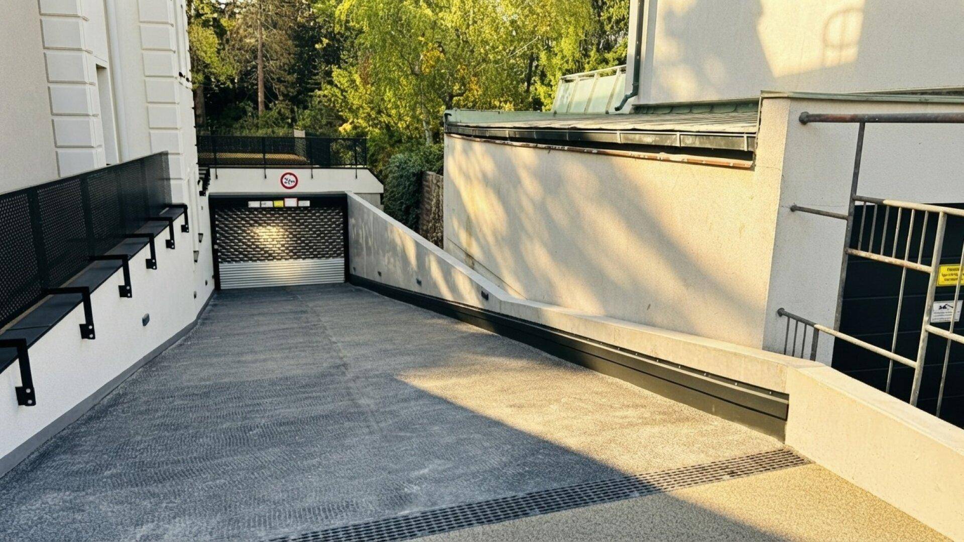 Zufahrt zur Tiefgarage mit Rolltor und Rampe.