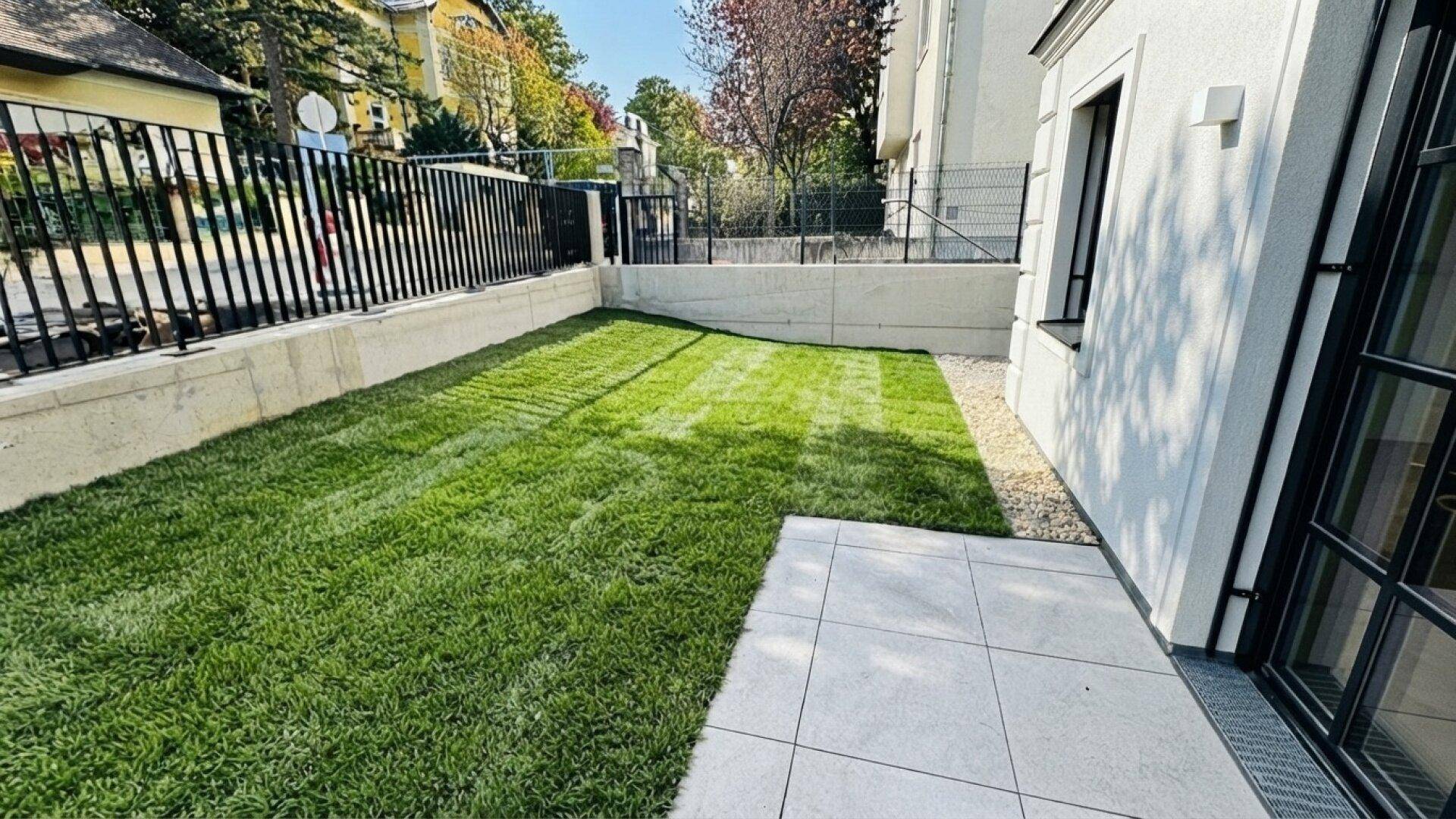 Kleiner privater Gartenbereich mit Rasenfläche und angrenzender Terrasse.