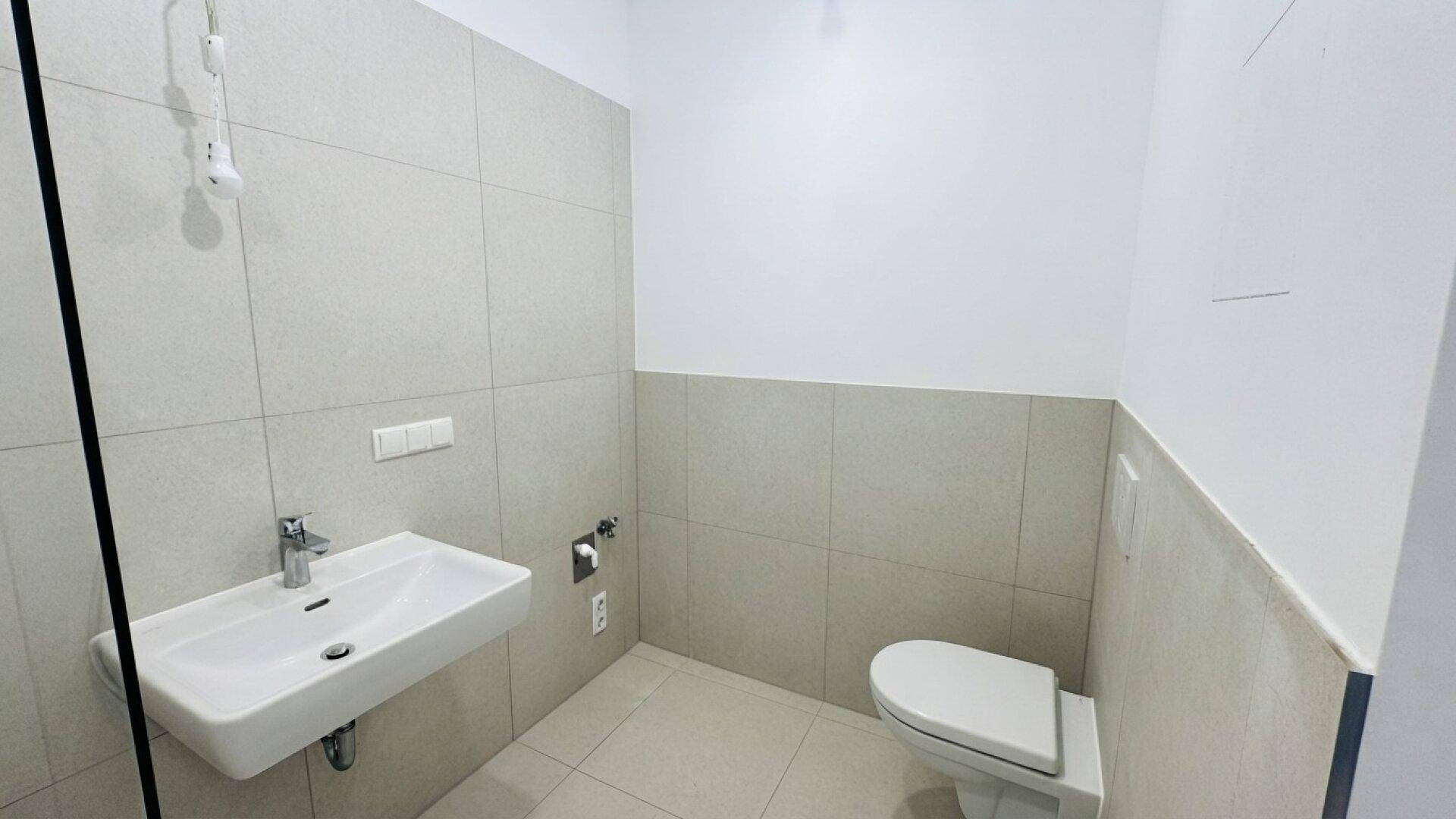 Modernes Badezimmer mit Wand-WC, Einzelwaschbecken und hellen Fliesen.