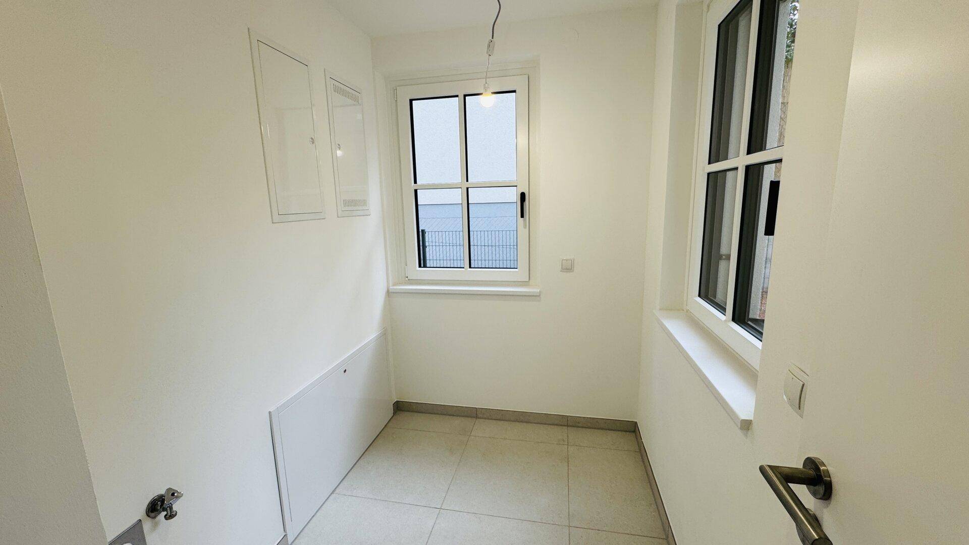 Kleiner Hauswirtschaftsraum mit Fenster und Fliesenboden, ideal für Lagerung oder Technik.