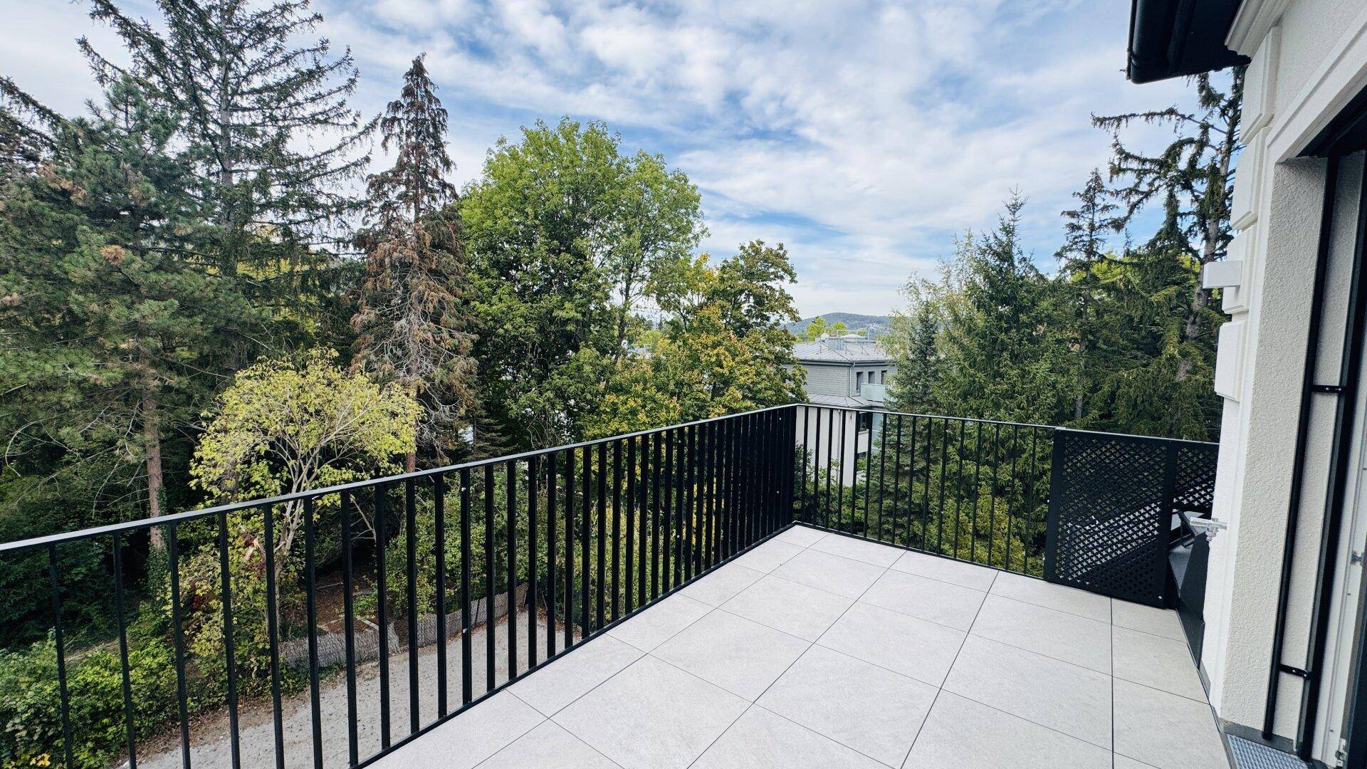 Geräumiger Balkon mit Fliesenboden und weitem Blick ins Grüne.