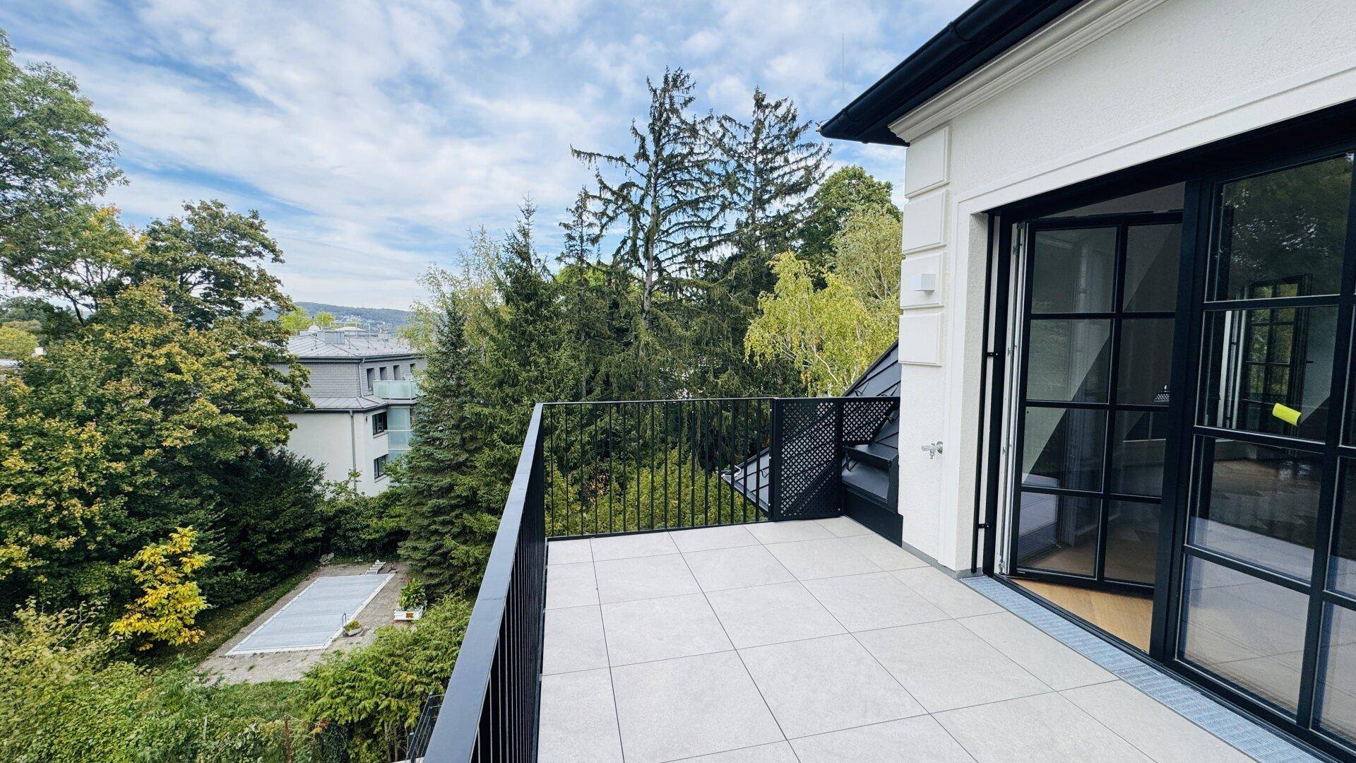 Großer Balkon mit Fliesenboden und weitem Blick über die Baumwipfel.
