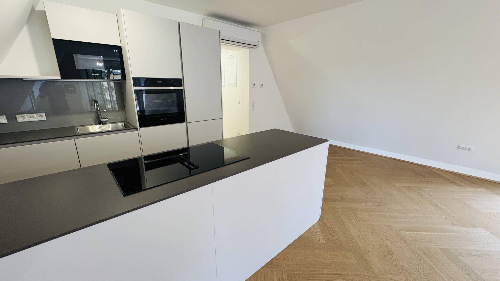 Moderne Einbauküche mit Kochinsel, integrierten Geräten und Dachschrägen.