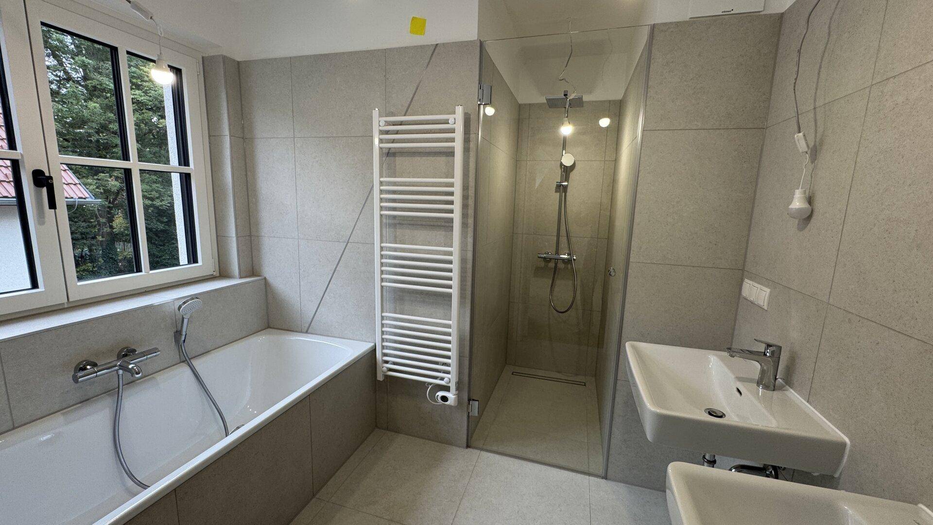 Modernes Badezimmer mit Badewanne, ebenerdiger Dusche und Fenster.