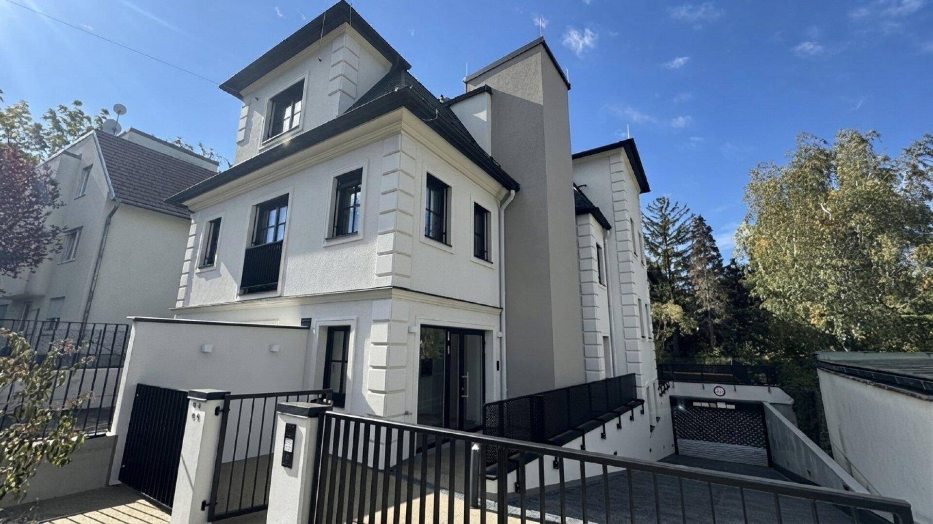Elegantes Mehrfamilienhaus mit Zufahrt zur Tiefgarage und modernem Eingangsbereich.