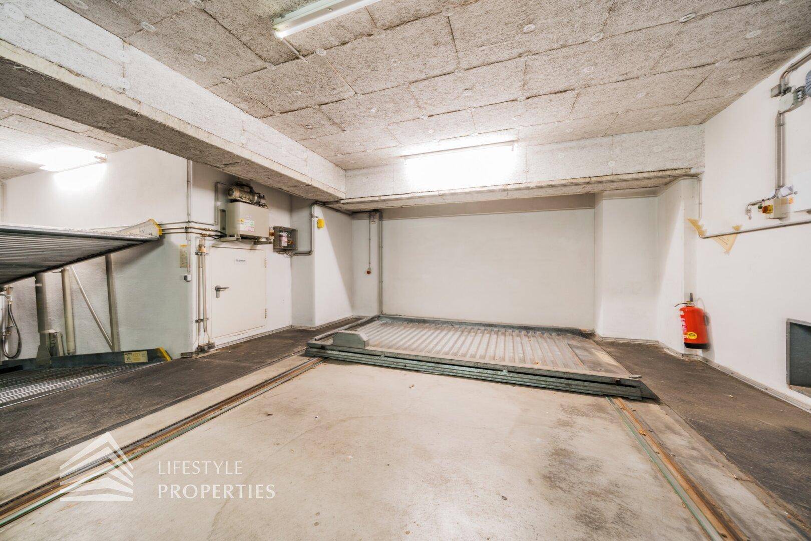Geräumige Tiefgarage mit zwei mechanischen Parksystemen und funktionaler Beleuchtung.
