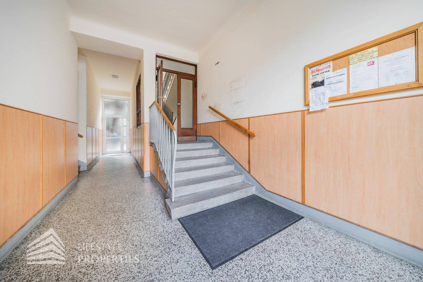 Gemeinschaftlicher Flur mit Treppenaufgang und Terrazzoboden im Altbau.