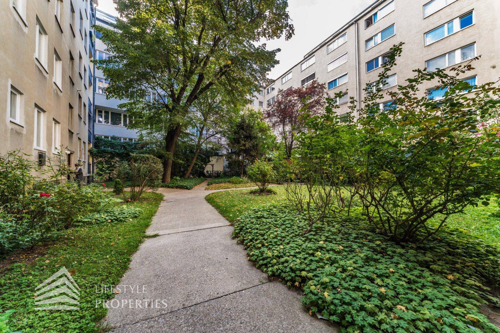 Gepflegter Gemeinschaftsgarten mit Wegen und üppiger Bepflanzung.