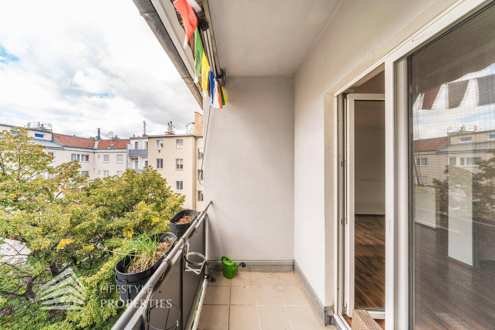 Kleiner Balkon mit Blick auf die umliegenden Gebäude und Bäume.