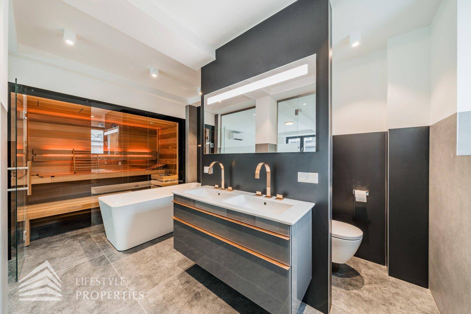 Luxuriöses Badezimmer mit Doppelwaschbecken, freistehender Badewanne, Sauna und modernen Armaturen.