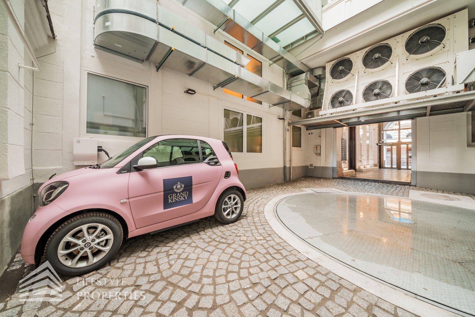 Überdachter Parkbereich mit Auto-Drehscheibe und industriellen Lüftungsanlagen in einem modernen Gebäude.