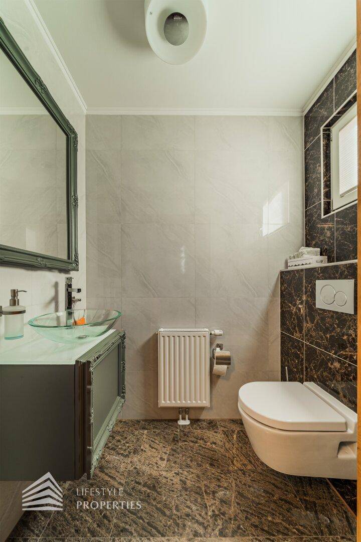 Modernes Gäste-WC mit stilvollem Waschbecken, Wand-WC und eleganten Fliesen an Wänden und Boden.