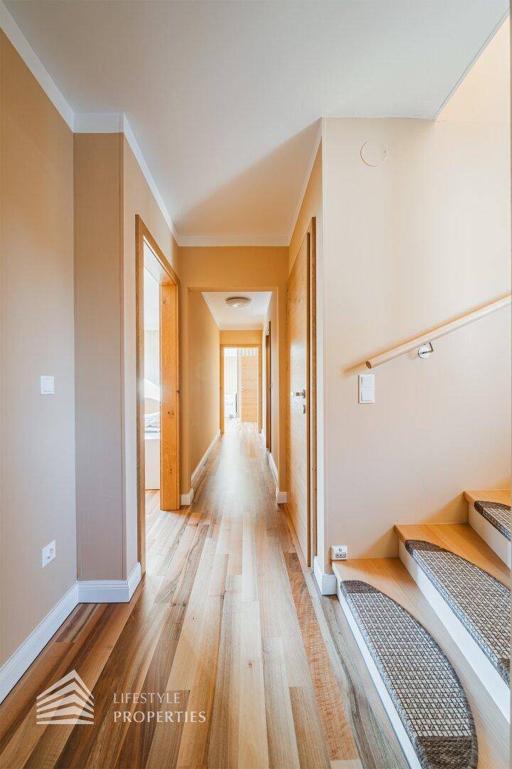 Langer, heller Flur mit Holzfußboden, der zu verschiedenen Zimmern und einer Treppe führt.