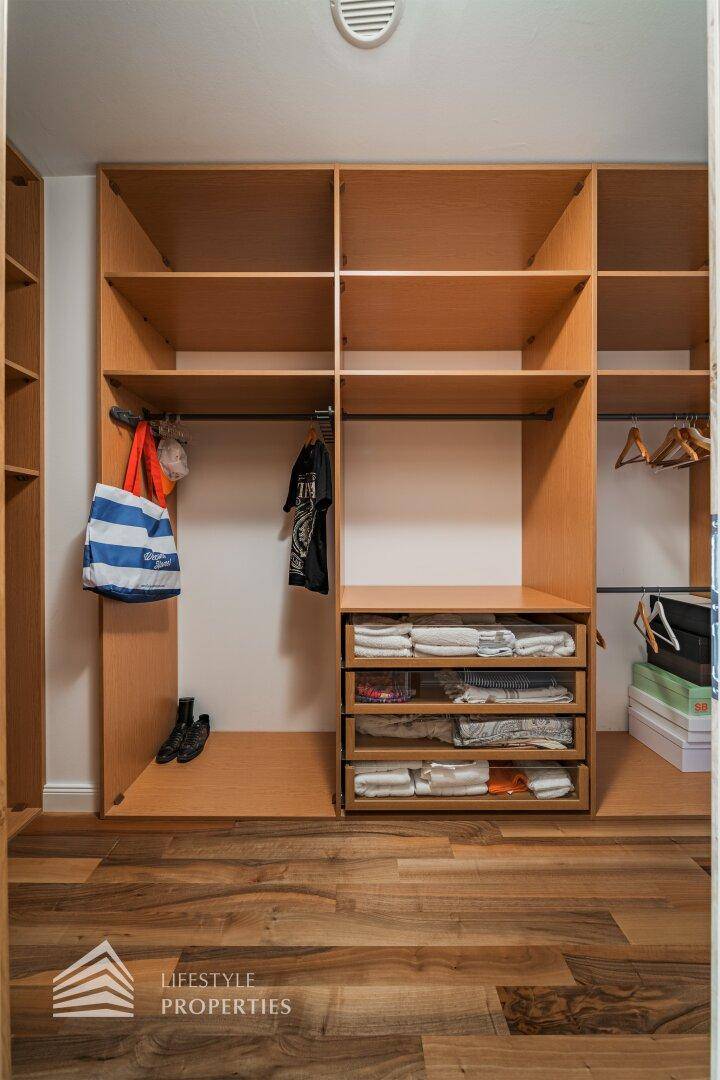 Praktischer begehbarer Kleiderschrank mit offenen Holzregalen und Schubladen für viel Stauraum.