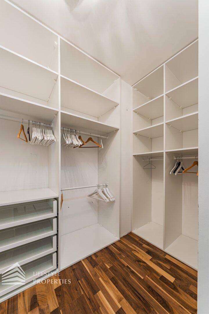 Geräumiger begehbarer Kleiderschrank mit vielen Regalen und Hängemöglichkeiten für Kleidung.
