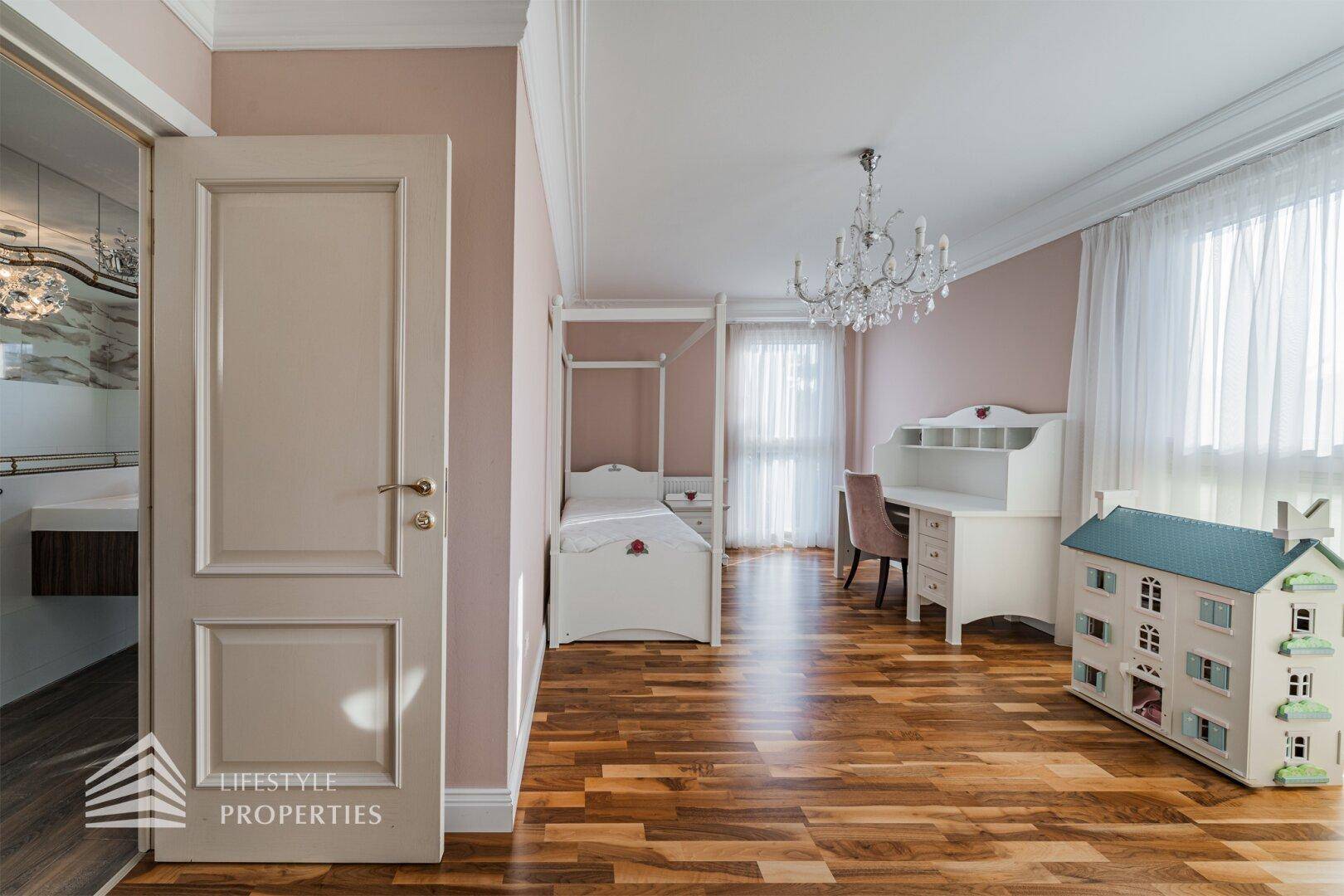 Kinderzimmer mit Himmelbett, Schreibtisch, Parkettboden und Zugang zu einem Badezimmer.
