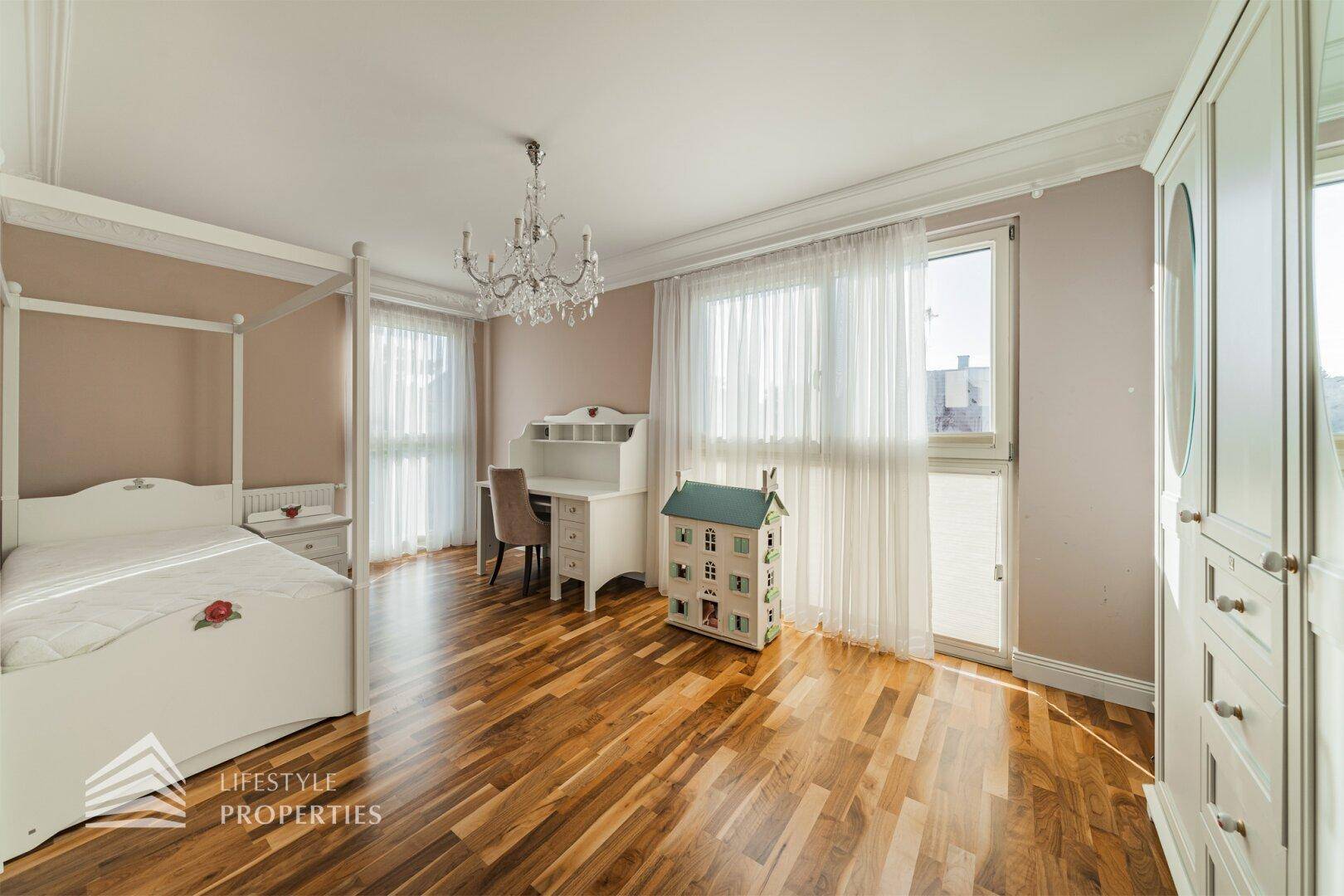 Helles Kinderzimmer mit Himmelbett, Schreibtisch, großem Kleiderschrank und Parkettboden.