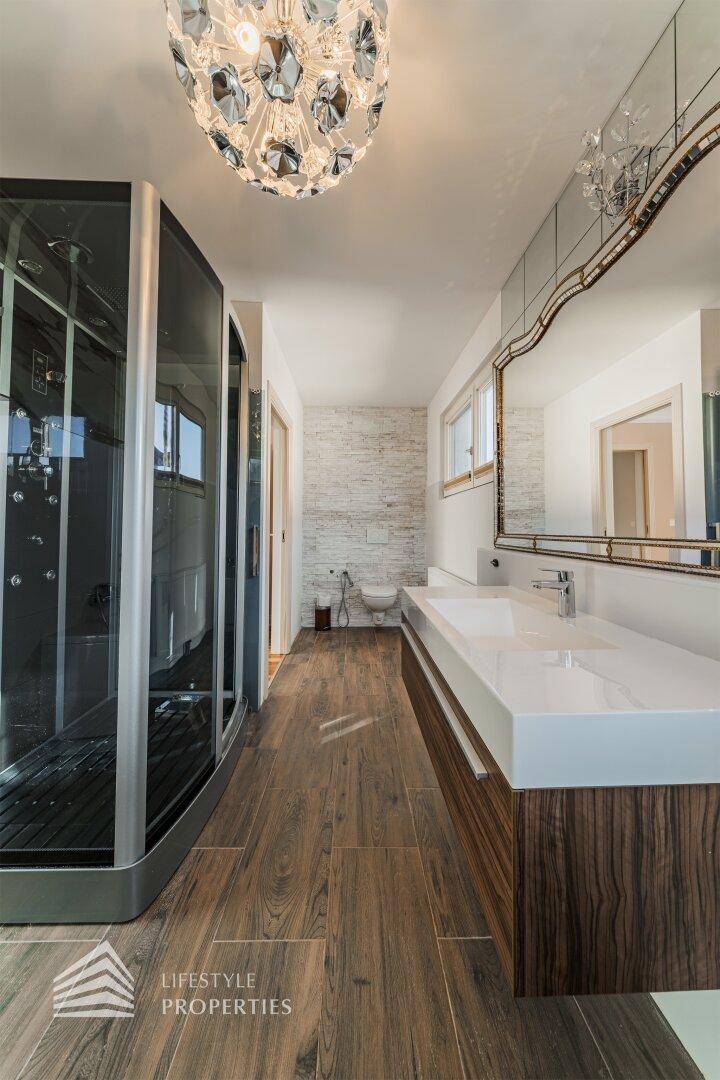 Geräumiges Badezimmer mit Doppelwaschbecken, großer Dusche und modernen Fliesen.