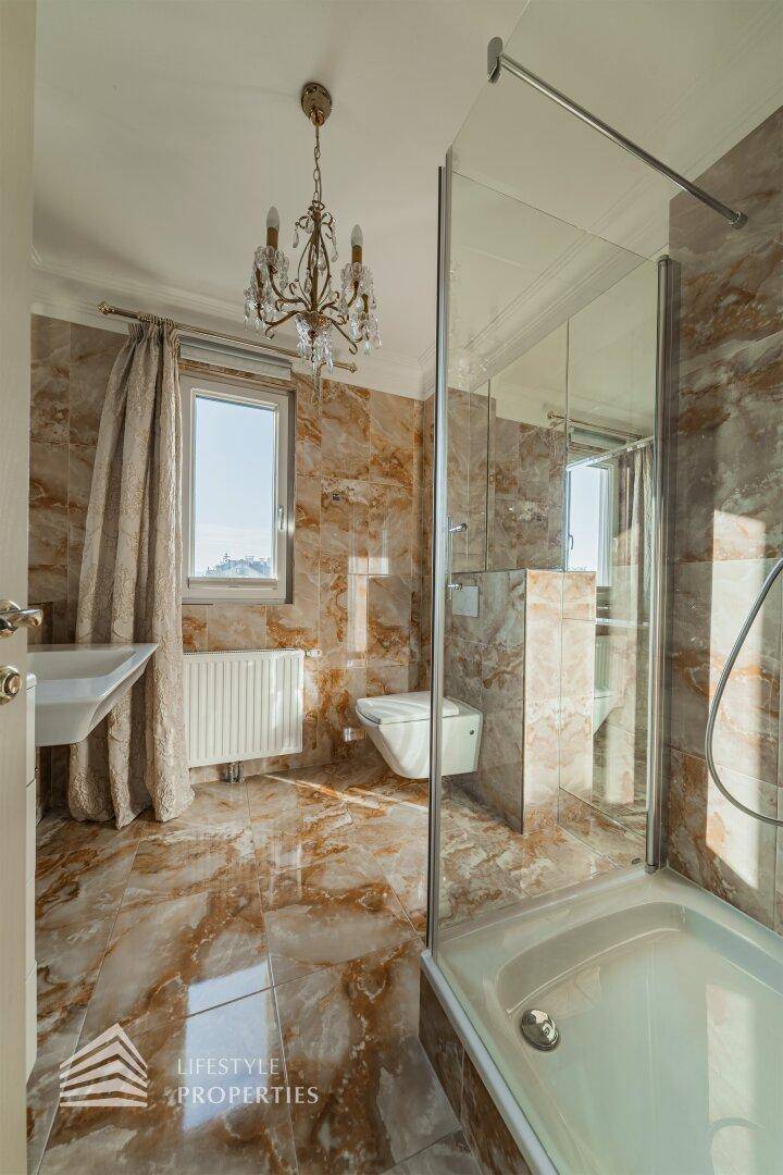 Badezimmer mit Dusche, WC, Waschbecken und eleganten Marmorfliesen an Wänden und Boden.
