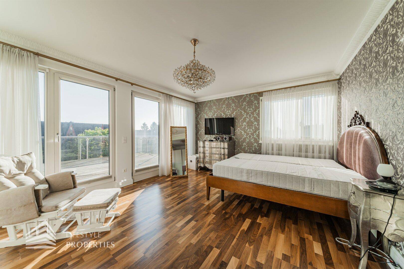 Lichtdurchflutetes Schlafzimmer mit Doppelbett, Parkettboden und direktem Terrassenzugang.