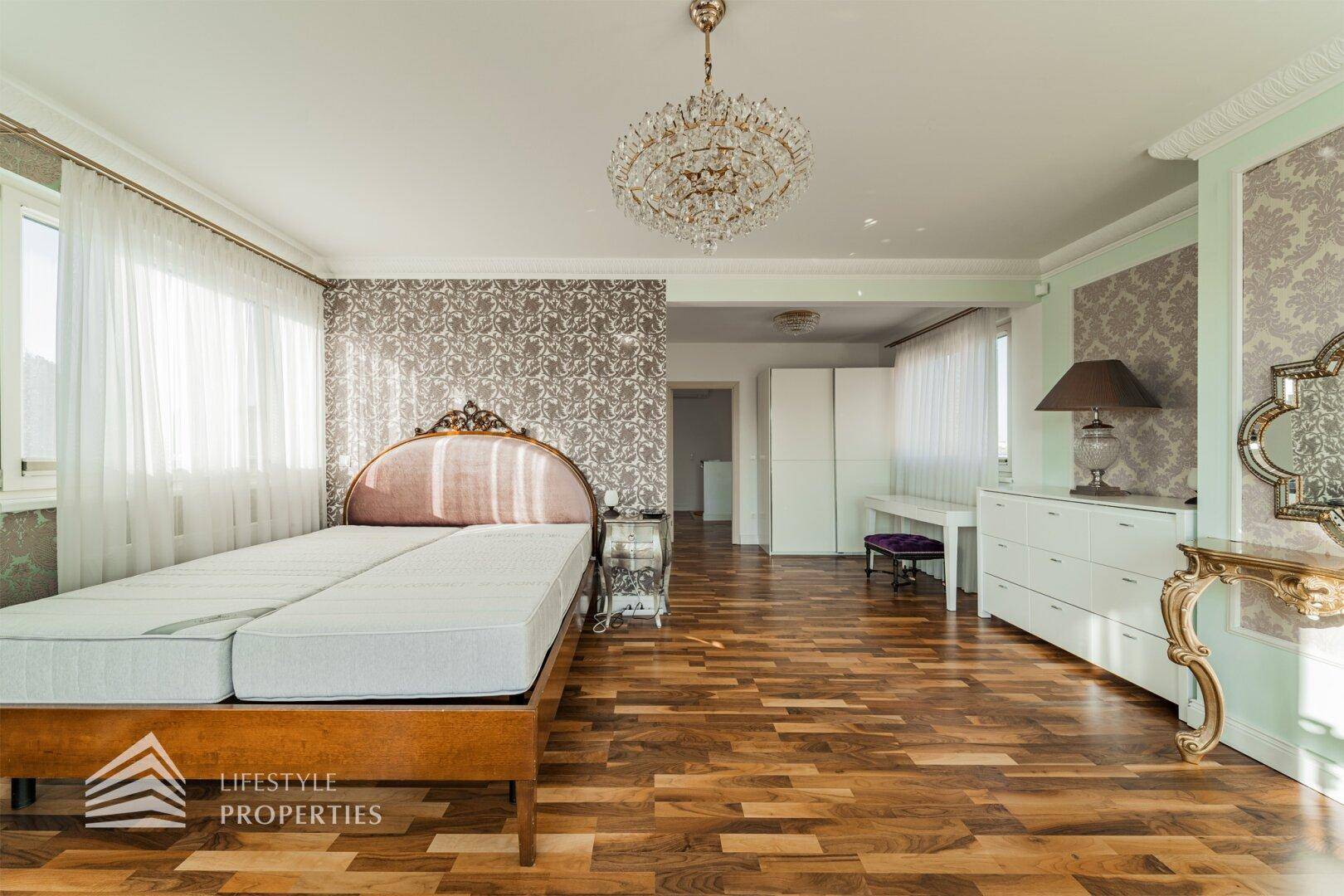 Geräumiges Schlafzimmer mit Doppelbett, Parkettboden, eleganten Möbeln und Einbauschränken.