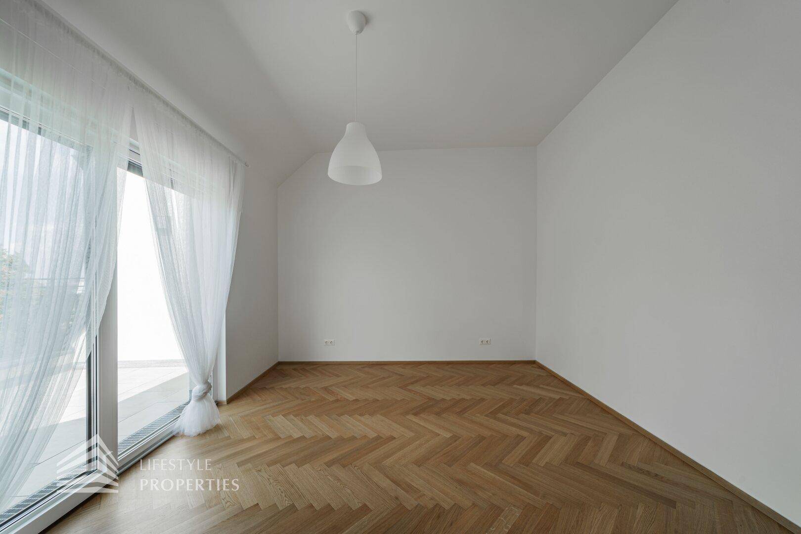 Schlafzimmer mit Fischgrätparkett und Zugang zu einem Balkon oder einer Terrasse, hell und modern.