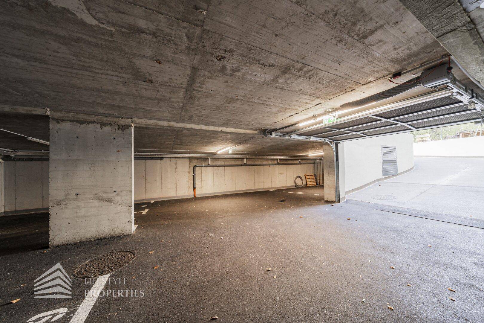 Zufahrt und Innenbereich einer Tiefgarage mit Betonstruktur und Beleuchtung.