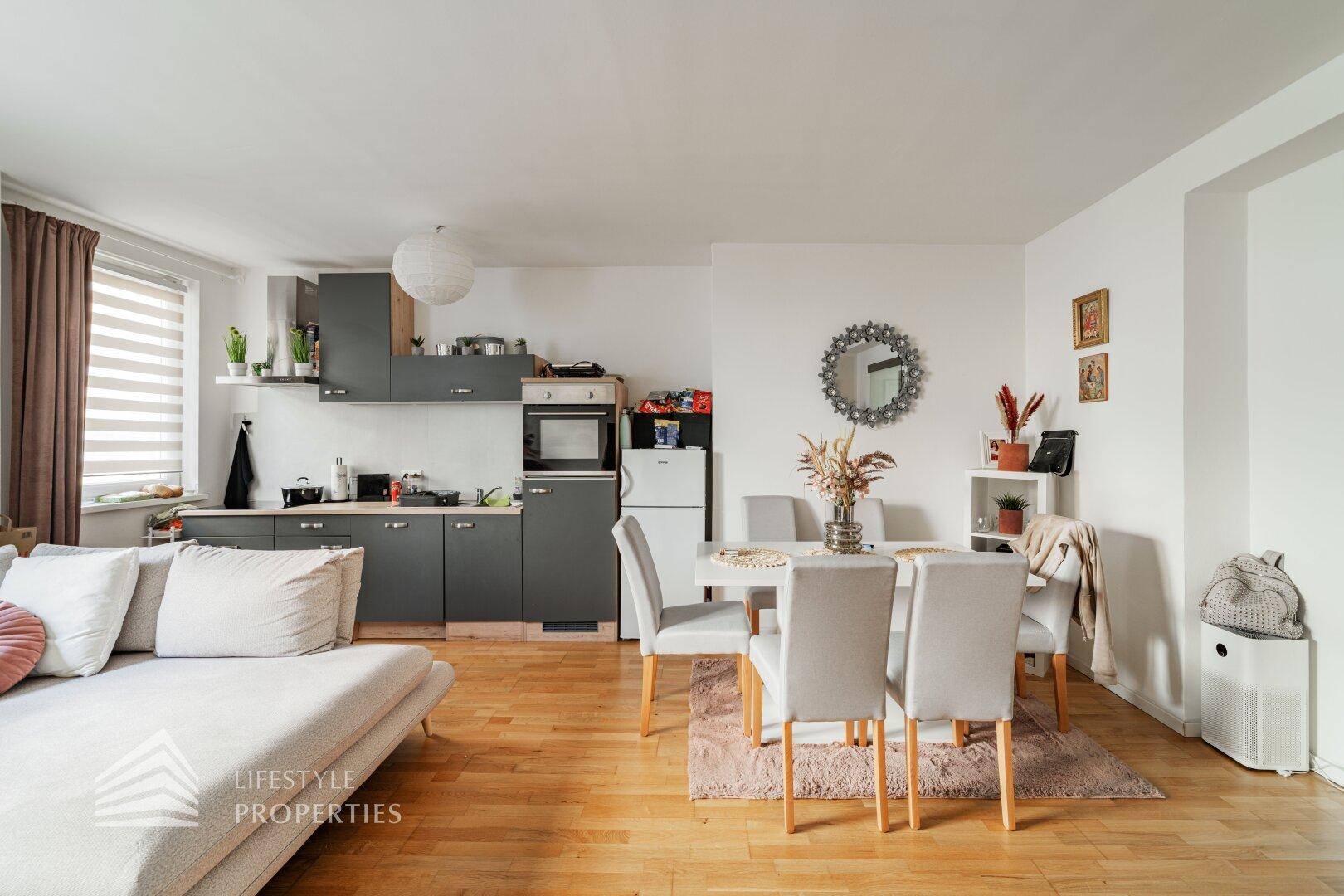 Funktionale Küche mit grauen Schränken und Essbereich, offen zum Wohnzimmer.
