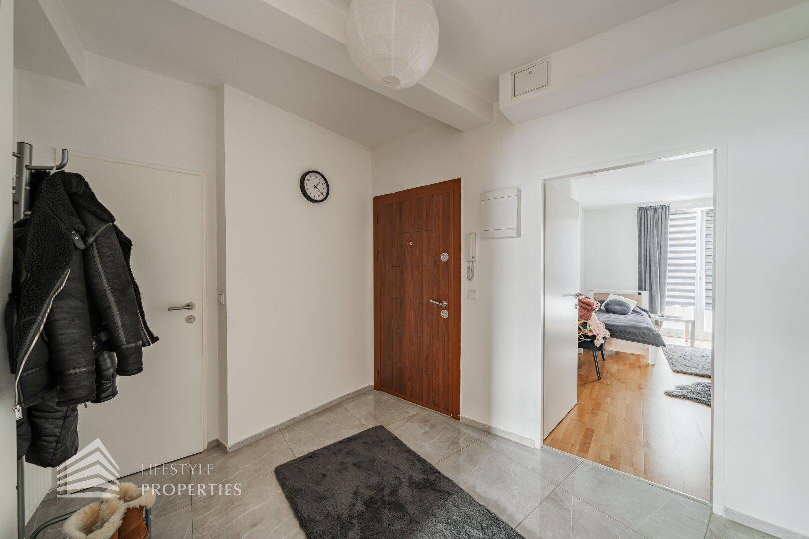 Geräumiger Flur mit Garderobe, Sicherheitstür und Blick in ein Schlafzimmer.