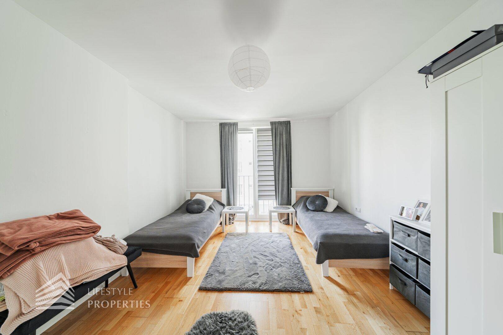 Freundliches Schlafzimmer mit zwei Einzelbetten und Fenster für viel Tageslicht.