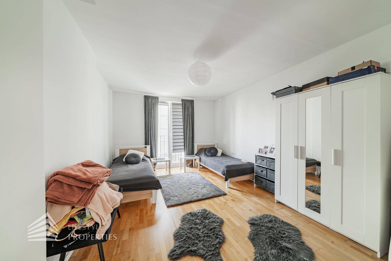Helles Schlafzimmer mit zwei Einzelbetten, großem Kleiderschrank und Parkettboden.