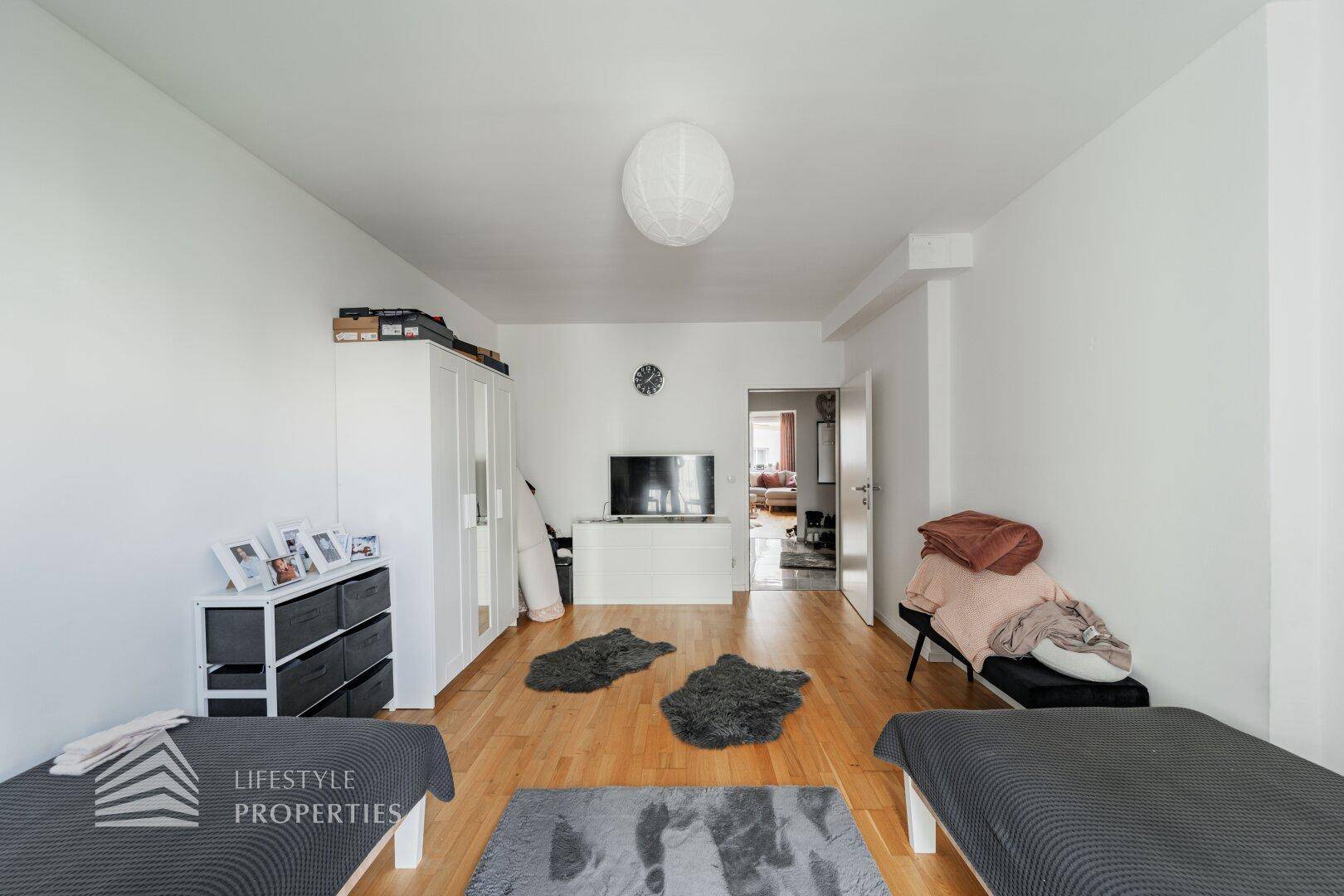 Geräumiges Schlafzimmer mit zwei Betten, Kleiderschrank und Blick in den angrenzenden Raum.