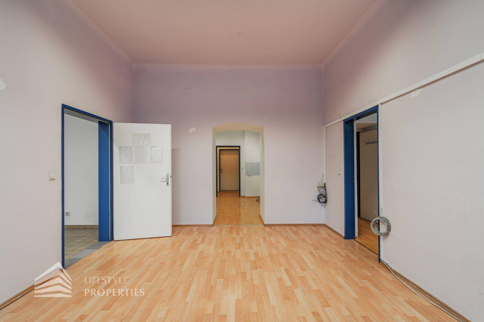 Großer, leerer Raum mit Holzboden und mehreren Türen, der vielseitige Nutzungsmöglichkeiten bietet.