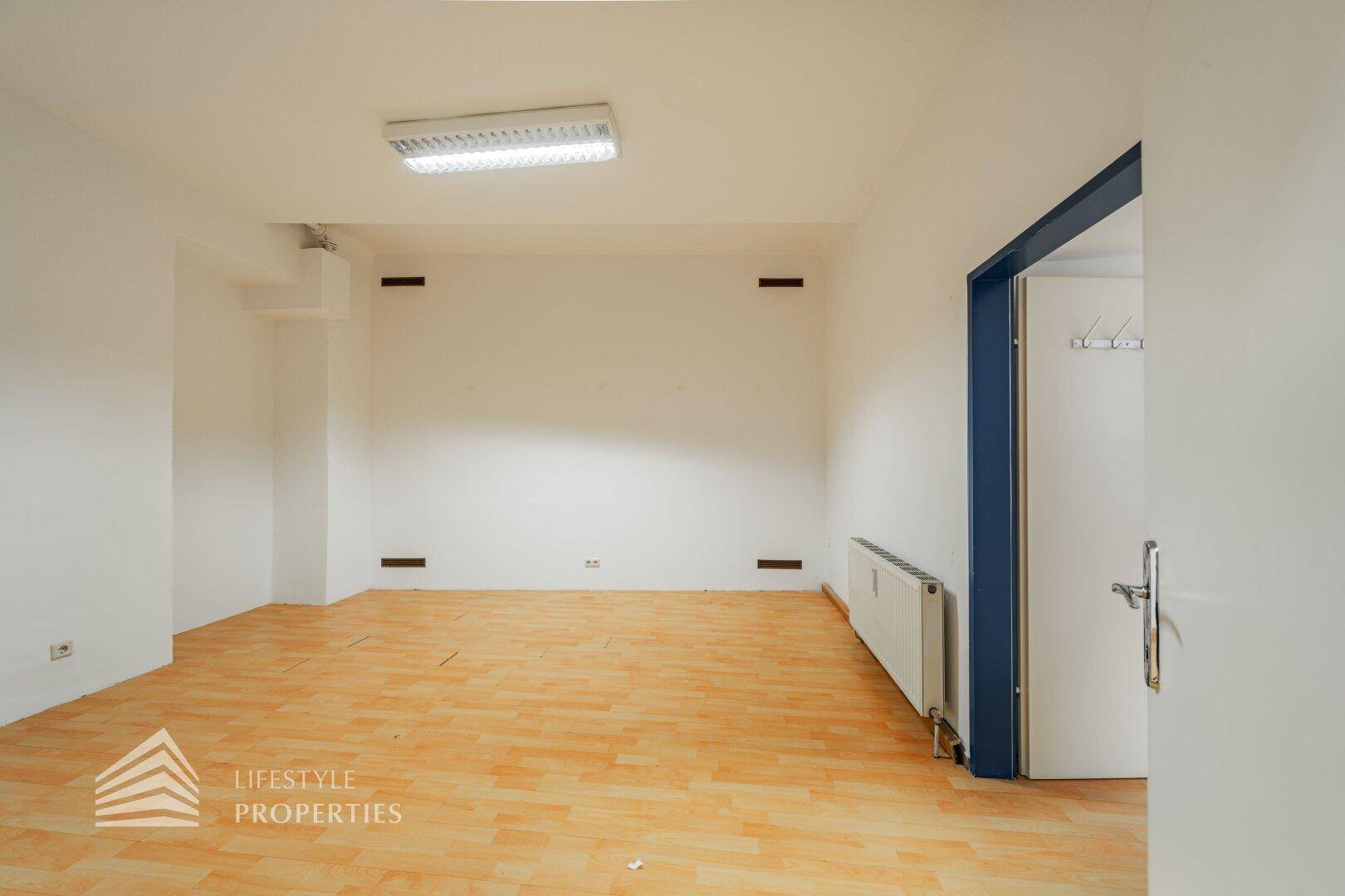 Heller Büroraum mit Holzboden und Heizkörpern unter den Fenstern, bereit für die individuelle Gestaltung.