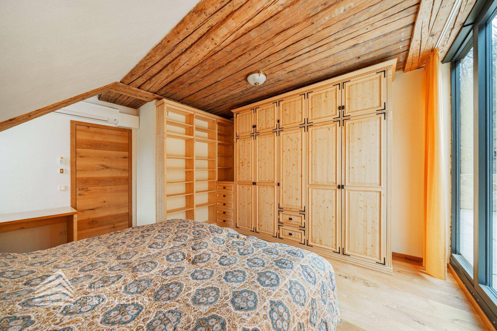 Schlafzimmer mit rustikaler Holzdecke, großen Einbauschränken und Holzboden.